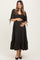 woman wearing a black floral maternity dress with puff sleeves and a tiered skirt, holding her baby bump