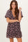 woman wearing a dark floral print short dress with ruffled sleeves and a v-neckline