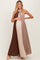 woman wearing a color-blocked pleated maternity maxi dress in brown and beige, gently holding her baby bump