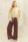 woman wearing a beige cropped sweatshirt with tie sleeves and brown wide-leg pants