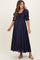 woman wearing a navy blue maternity maxi dress with puff sleeves and a smocked bodice, showcasing a baby bump