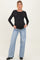 woman wearing a black long sleeve maternity top and light blue wide-leg jeans, showcasing her baby bump