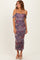 woman wearing a purple floral ruched midi dress with off-shoulder straps and side slits