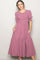 woman wearing a mauve puff sleeve maxi dress with a smocked bodice and tiered skirt, posing with hands in pockets