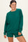 woman wearing a green oversized long sleeve sweatshirt with matching shorts, smiling against a neutral background