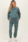 woman wearing a teal maternity sweatshirt and matching sweatpants with pockets, styled for comfort