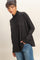 woman wearing a black turtleneck loose fit sweater with long sleeves and blue jeans