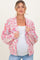 woman wearing a pink and white chunky knit maternity cardigan over a white top and showing her baby bump