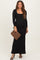 woman wearing a black long sleeve maternity dress and holding a leopard print clutch, showcasing her baby bump