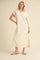 woman wearing a beige short sleeve polo-style dress with a side slit and standing in slide sandals