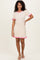 woman wearing a beige ribbed knit short sleeve dress with pink ruffle trim on sleeves and hem