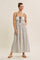 woman wearing a white maxi dress with navy patterns, adjustable spaghetti straps, and side pockets