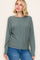 woman wearing a green long sleeve sweater and blue jeans