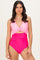 woman wearing a pink and fuchsia color-blocked one-piece swimsuit with a twist front detail