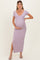 woman wearing a lavender maternity maxi dress with a deep v-neck and a side slit, gently cradling her baby bump