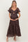 woman wearing a dark floral print maternity dress with a twist front and ruffled sleeves, holding her baby bump