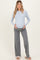 woman wearing a light blue long sleeve maternity top and gray wide-leg pants, cradling her baby bump