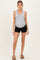 woman wearing a gray ribbed tank top and black maternity shorts, showing her baby bump