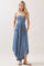 woman wearing a light blue strapless maxi dress with a smocked bodice and pockets, standing in a relaxed pose