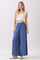 woman wearing a white cropped tank top and flowy blue wide-leg pants with an elastic waistband