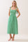 woman wearing a green gingham midi dress with tie straps and pockets, standing against a light background