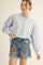 woman wearing a light blue button-up blouse with puff sleeves and denim shorts featuring strawberry embroidery
