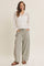 woman wearing a white long sleeve crochet top and gray striped wide-leg pants with pockets