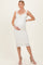 woman wearing a white lace maternity dress with ruffled straps and a fitted silhouette, holding her baby bump