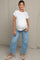 woman wearing a white maternity t-shirt and light blue wide-leg jeans, showing her baby bump