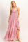 woman wearing a pink halter neck maxi dress with ruffle details and a high slit
