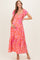 woman wearing a pink and orange floral maternity maxi dress and holding her baby bump