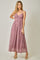woman wearing a floral patterned maxi dress in shades of pink with a twisted front detail and spaghetti straps
