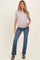 woman wearing a light gray short sleeve maternity top and blue flared jeans with a visible baby bump