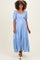 woman wearing a light blue polka dot maternity dress with puff sleeves and a tiered skirt, highlighting her baby bump