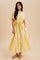 woman wearing a light yellow short sleeve maxi dress with a tie waist and ruffle trim