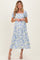 woman wearing a floral blue and white maternity dress with short puff sleeves and a square neckline