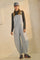 woman wearing blue and white striped overalls with side buttons and a long-sleeve gray top, paired with a gray cap and sneakers