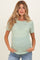woman wearing a striped green maternity top with short sleeves and a baby bump, posing with hands in pockets