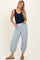 woman wearing a navy blue tank top and light blue striped elastic waist pants with gathered cuffs