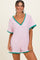 woman wearing a pink and white striped short romper with green trim and a v-neckline