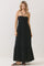 woman wearing a black maxi dress with a ruffled bodice and spaghetti straps, standing against a neutral background