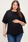 woman wearing a black oversized maternity top and holding her baby bump