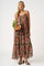 woman wearing a floral maxi dress with a tiered design and holding a bouquet of flowers