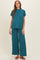 woman wearing a teal maternity two-piece outfit with a loose-fitting top and wide-leg pants, displaying a baby bump