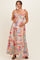 woman wearing a colorful floral maternity maxi dress with ruffled straps and holding her baby bump