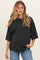 woman wearing a black oversized maternity top and blue jeans, with a visible baby bump