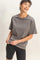 woman wearing a gray short sleeve t-shirt and black bike shorts, smiling while holding the t-shirt hem