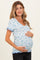 woman wearing a light blue floral maternity top with short ruffled sleeves and holding her baby bump