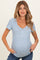 woman wearing a light blue striped maternity top and holding her baby bump