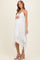woman wearing a white lace maternity dress with a high-low hem and holding her baby bump